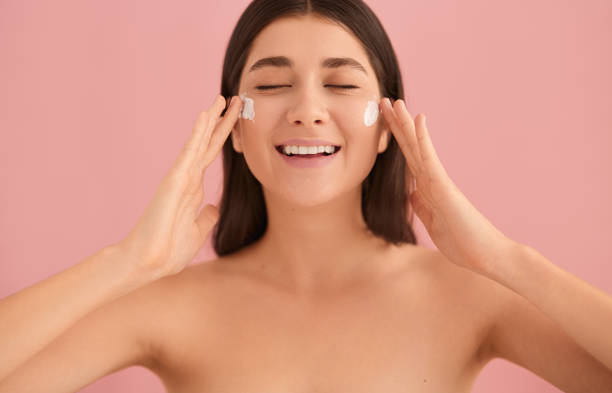 istock Smiling woman applying cream on face 1479201609