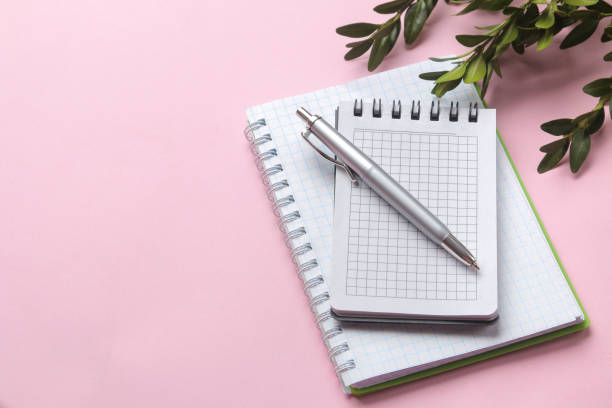 istock Notebooks with a pen and green leaves on a delicate pink background. top view 1479202394