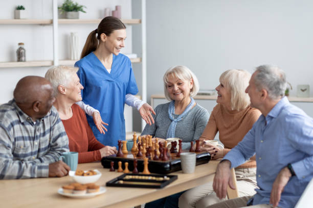 istock Friendly nurse talking to elderly people playing table games 1479214725