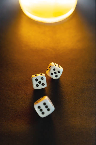 istock Three dice rolled on the table, on a black background with orange reflections. Casino concept,night,roulette,money - selective approach,details. 1479229559