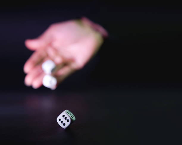 istock White dice rolled by a woman's hand on a black background – selective focus. Concept of gambling. 1479229584