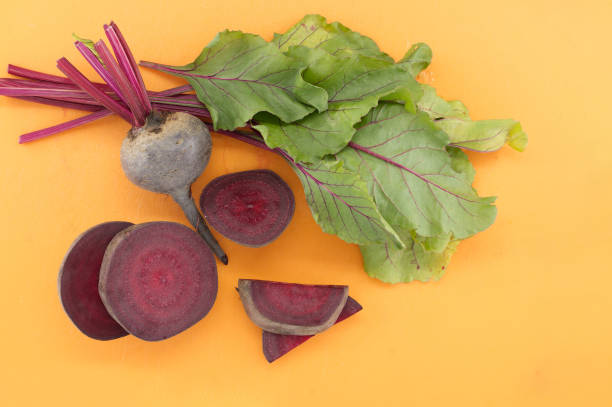 Beetroot with green leave on yellow cutting board stock photo