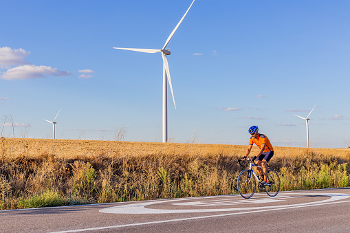 Valladolid. Spain. Road cyclist rolling next to wind power towers.