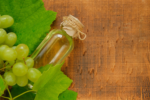 Grape seed oil bottle and green grapes on a wooden background.Base cosmetic oil for massage and care for face and body.Organic Natural Bio Grape Seed Oil