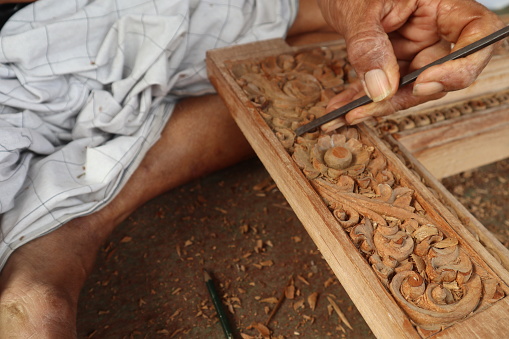 carpenter carves the pattern on the wood carefully