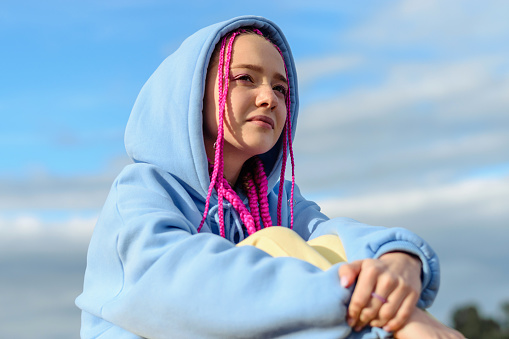 Portrait of a caucasian teenage girl with pink braids against the blue sky.Summer concept.Generation Z style.