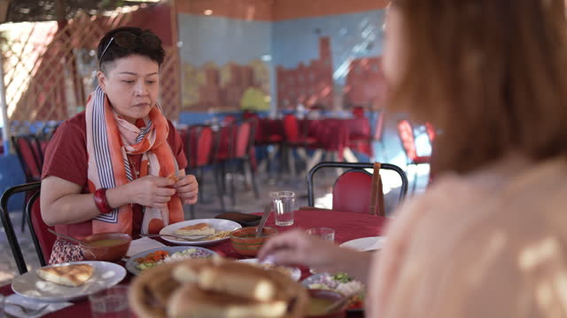 2 Asian Chinese female tourist enjoying moroccan food at patio in restaurant