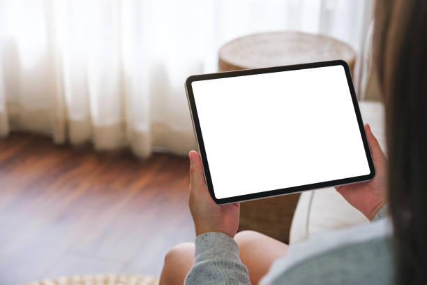 istock Mockup image of a woman holding digital tablet with blank desktop screen while lying on a sofa at home 1479258302