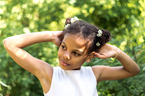 Portrait of a cute African-American girl with flowers in her hairstyle on a spring day.Spring concept,diversity people.
