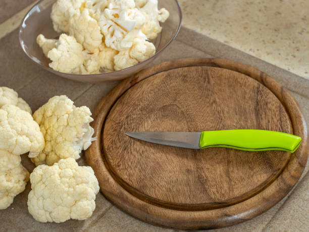 istock Fresh cauliflower, a wooden cutting board and a knife on the kitchen table. Flat layout. Place for text. The concept of cooking fresh vegetables in the home kitchen. 1479265476