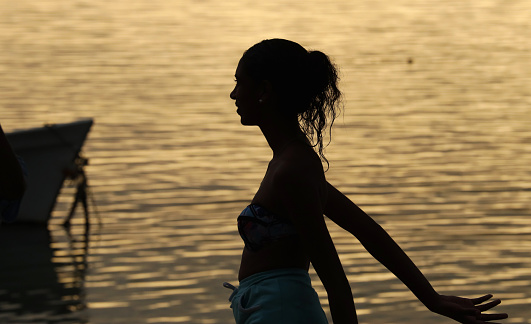 Albion, Mauritius - April 02, 2023: Silhouette of young woman at the beach in the West of Mauritius during sunset.