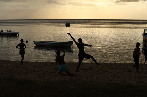 Albion, Mauritius - April 02, 2023: Silhouettes of young people at the beach in the West of Mauritius during sunset.