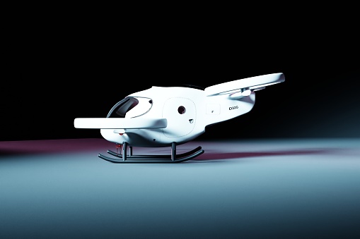 Side view of an electric vertical take-off and landing aircraft. The electric air vehicle is white and has a modern design. The aircraft is parked in a dark room and illuminated by a bright spotlight.