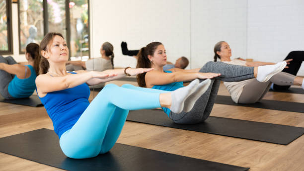 Young woman doing v-sit during warming up in pilates studio