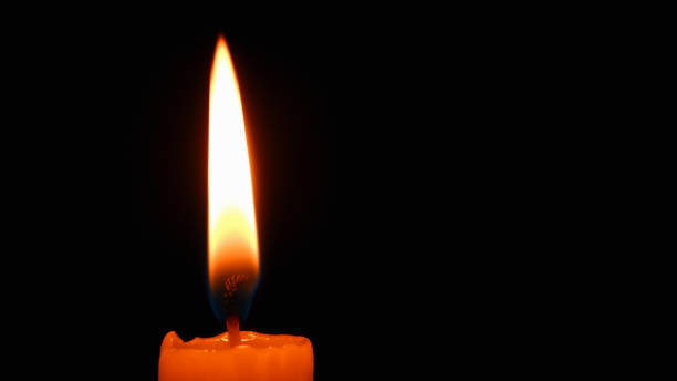 istock Candle flame on black background. Single lit candle with quite flame. Dramatic burning candle flame on a black background with copy space 1479286415