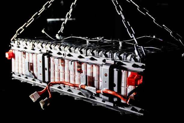 Large assembly of EV battery cells on their own steel subframe. The frame shows the wires for the unit's BMS, as well as the wiring for temperature sensors and power terminals. The assembly is suspended by chains on a special crane for maintenance. Selective focus gran ensamblaje de celdas de batería ev en su propio bastidor auxiliar de acero. el marco muestra los cables para el bms de la unidad, así como el cableado para sensores de temperatura y terminales de potencia. el conjunto está suspendido por cadenas en