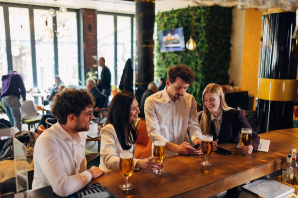 istock Four smiling business people hanging out in a pub, drinking beer, using a mobile phone 1479288153