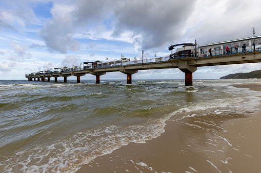 Miedzyzdroje, Poland - September 15, 2022: Miedzyzdroje pier, long wooden jetty entering the Baltic Sea from the beach, beautiful seaside landscape. Cloudy sky and windy weather
