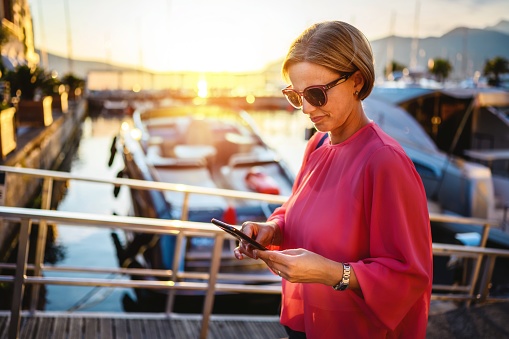 Mature woman using smartphone outdoors in port