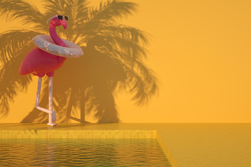 Inflatable flamingo and swimming pool, summer holiday travel concept on yellow background