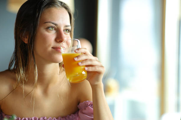 istock Woman drinking orange juice looking through a window 1479296137