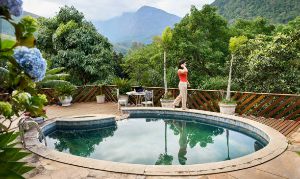 Young woman walking over a swimming pool wall in back yard of holiday home