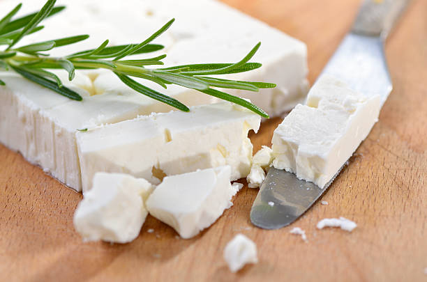 Greek feta cheese Typical Greek feta cheese made of goat milk on a wooden cutting board with a knife master bitter stock pictures, royalty-free photos & images