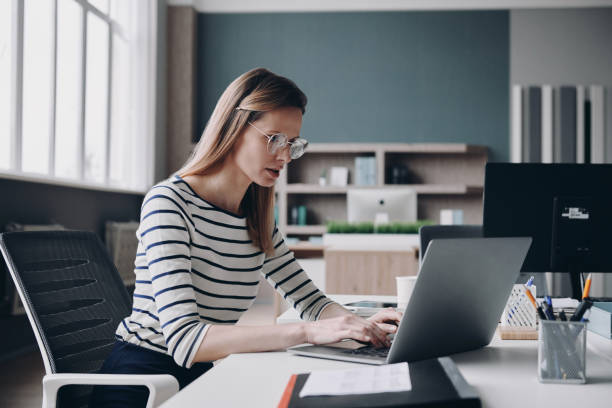 istock Confident young businesswoman using laptop while sitting at her working place in the office 1479313932