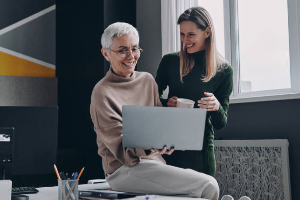 istock Two happy women using laptop and communicating while working in office together 1479314316