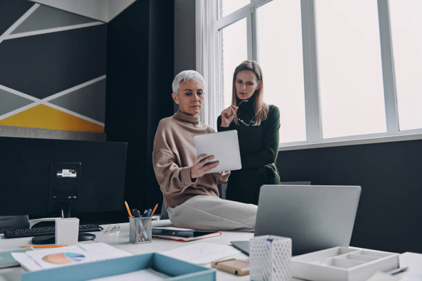 istock Two confident businesswomen using digital tablet while working in the office together 1479314345