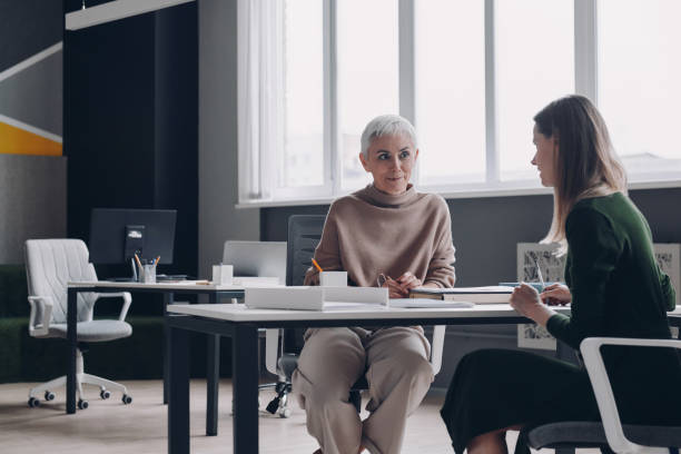 Woman having interview with confident HR manager while sitting at the office desk together stock photo