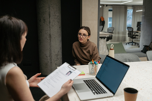 Photo of a young woman having a job interview. The female hiring manager is interviewing her.