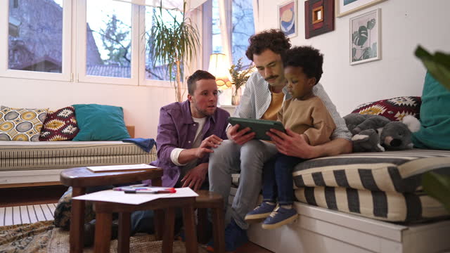 Gay couple looking at something on the tablet with their son