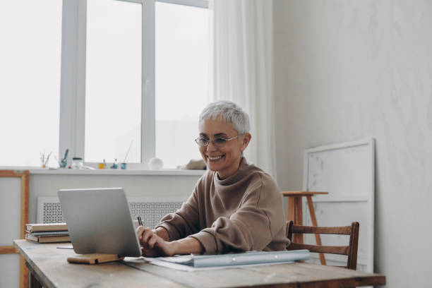 istock Senior businesswoman using digital tablet and smiling while sitting at her working place 1479316580
