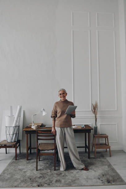 istock Happy senior woman holding digital tablet while standing near her working place 1479316976