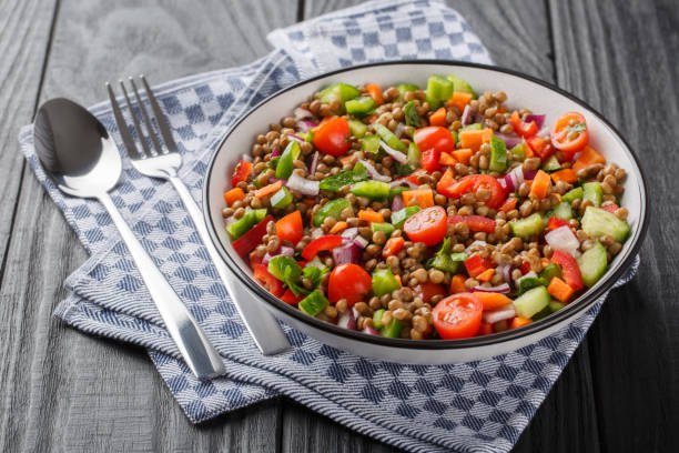 Vegetable salad with boiled lentils seasoned with olive oil close-up in a plate. Horizontal stock photo