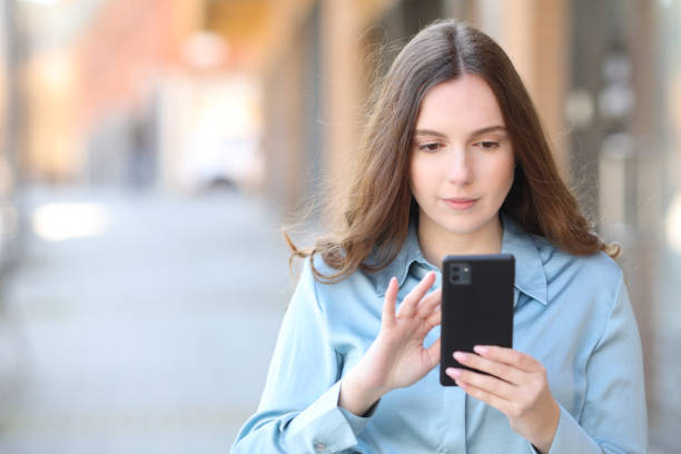 istock Serious woman using phone walking in the street 1479324123