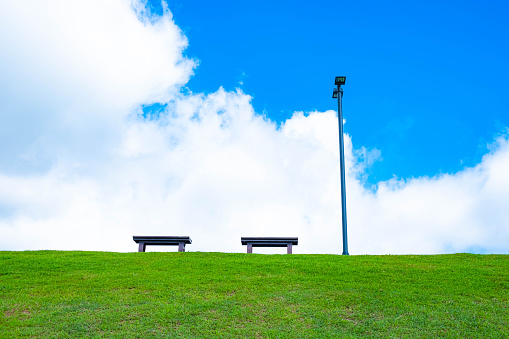 Benches on small hill with blue sky and white cloud in the background