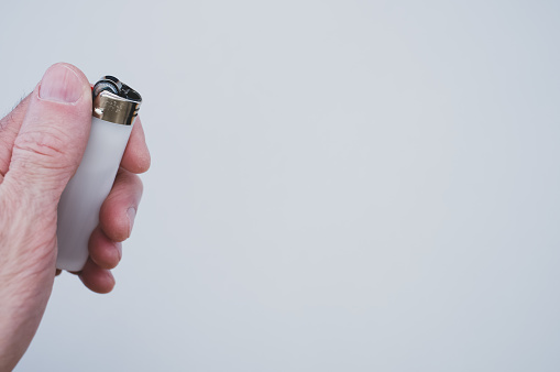 A closeup shot of a person holding a lighter over a grey surface