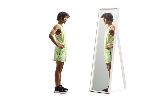 African american man in sportswear standing in front of a mirror isolated on white background