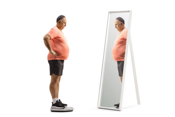 istock Mature man with a big belly standing on a weight scale and looking at a mirror 1479330009