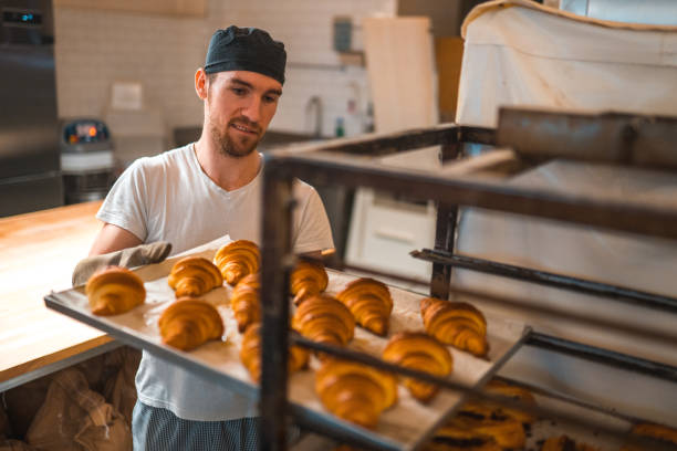 istock Artisan Baker Putting Freshly Baked Croissants Onto A Rack 1479330212