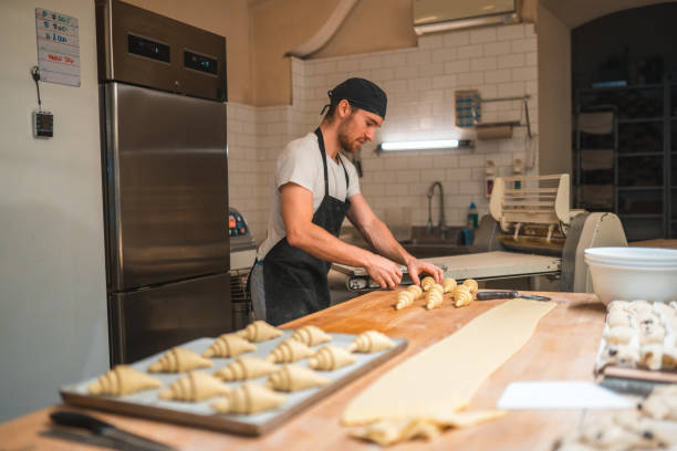 istock Artisan Baker Rolling Up Croissants In A Bakery 1479332428