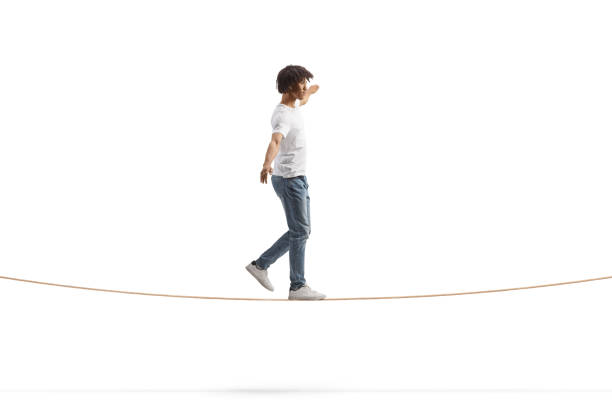 Immagine di profilo a figura intera di un giovane afroamericano che cammina su una corda tesa e mantiene l'equilibrio - foto stock