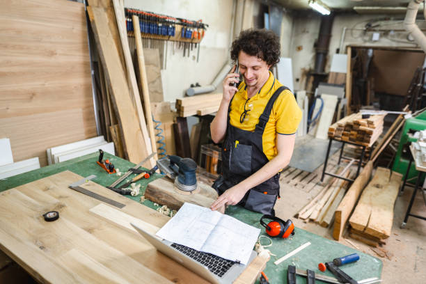 Carpenter talking on the phone while working in the woodshop