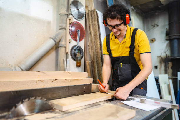 Carpenter using circular saw on a piece of wood in workshop