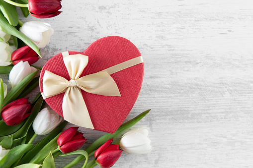 Mother’s Day and Valentine’s Day concept with red and white tulips and heart shaped gift box