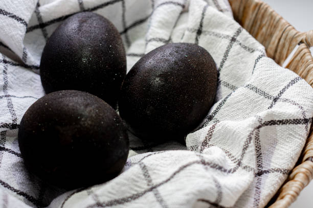 istock Black shiny easter eggs on a white towel in a brown basket on white background 1479337573