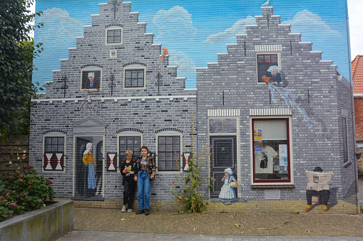 Zierikzee, Zeeland, Netherlands , August 27th 2020 - House facade with artistic mural painting on Plein Montmaertre in the middle of the city , Two children in game handcuffs are standing in front