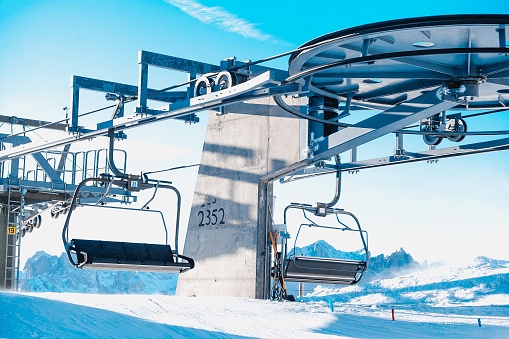 A scenic view of two ski lifts in the mountains, surrounded by snow-covered terrain
